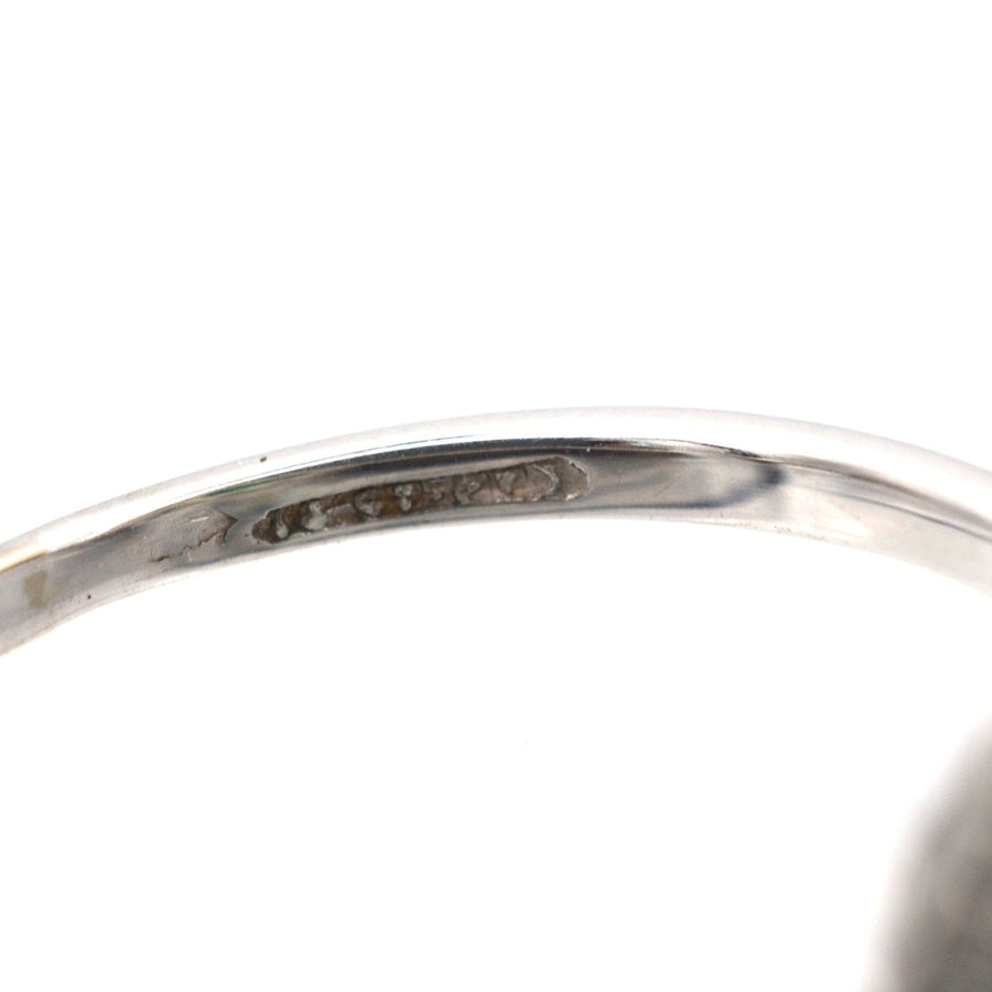 Close-up of the inner band of an Art Deco emerald and diamond ring, showcasing the hallmark and detailing.