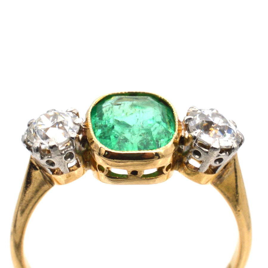 Art Deco platinum and 18ct gold three stone ring featuring a vibrant emerald and bright diamonds, ideal for engagement or anniversary.