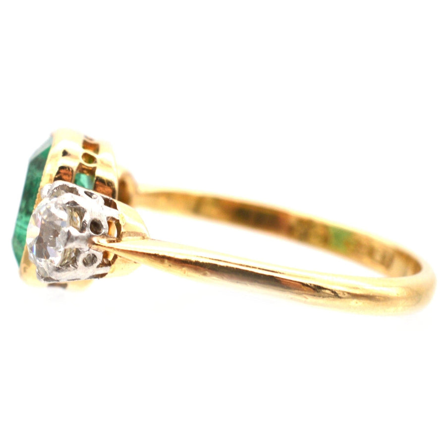 Art Deco three stone ring featuring an emerald, set in 18ct gold with diamond accents in platinum.