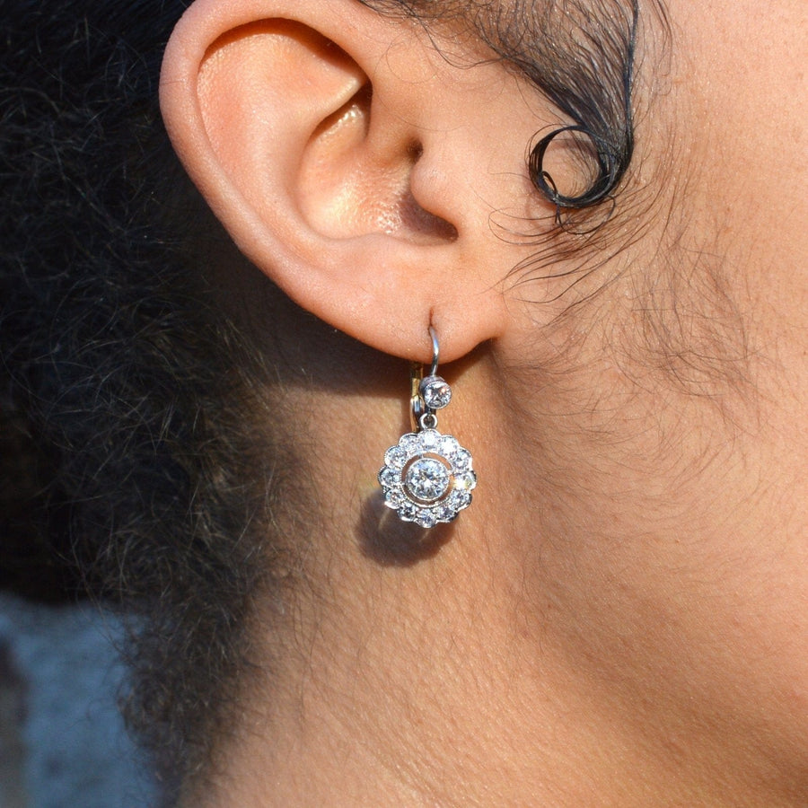 Art Deco platinum and gold diamond cluster drop earrings worn on ear, showcasing elegant design and sparkling gems.