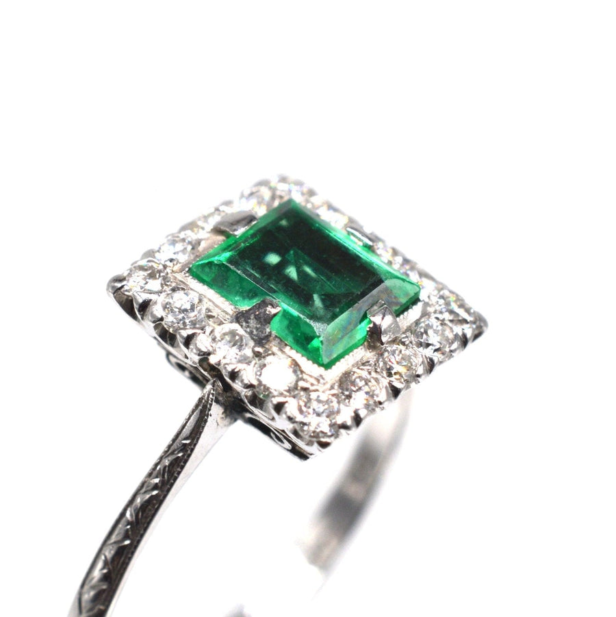 Art Deco platinum ring featuring a rectangular emerald surrounded by diamonds, ideal for engagement.