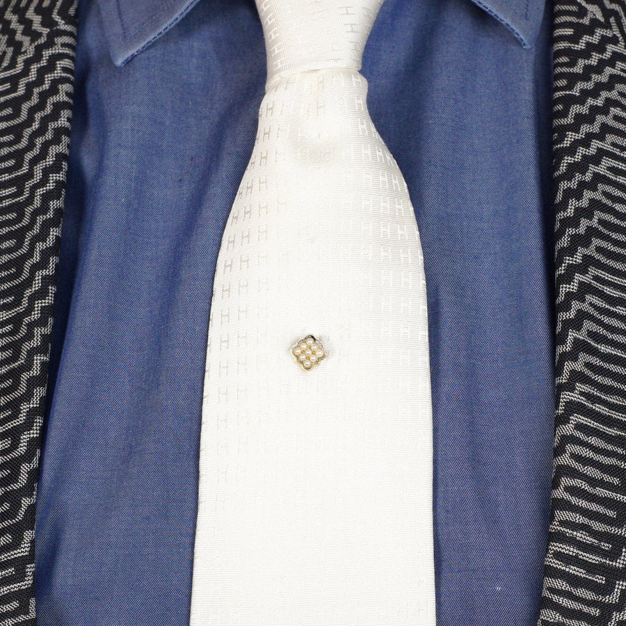 Edwardian 15ct gold natural split pearl diamond-shaped cluster tie pin on a white tie with a blue shirt backdrop.
