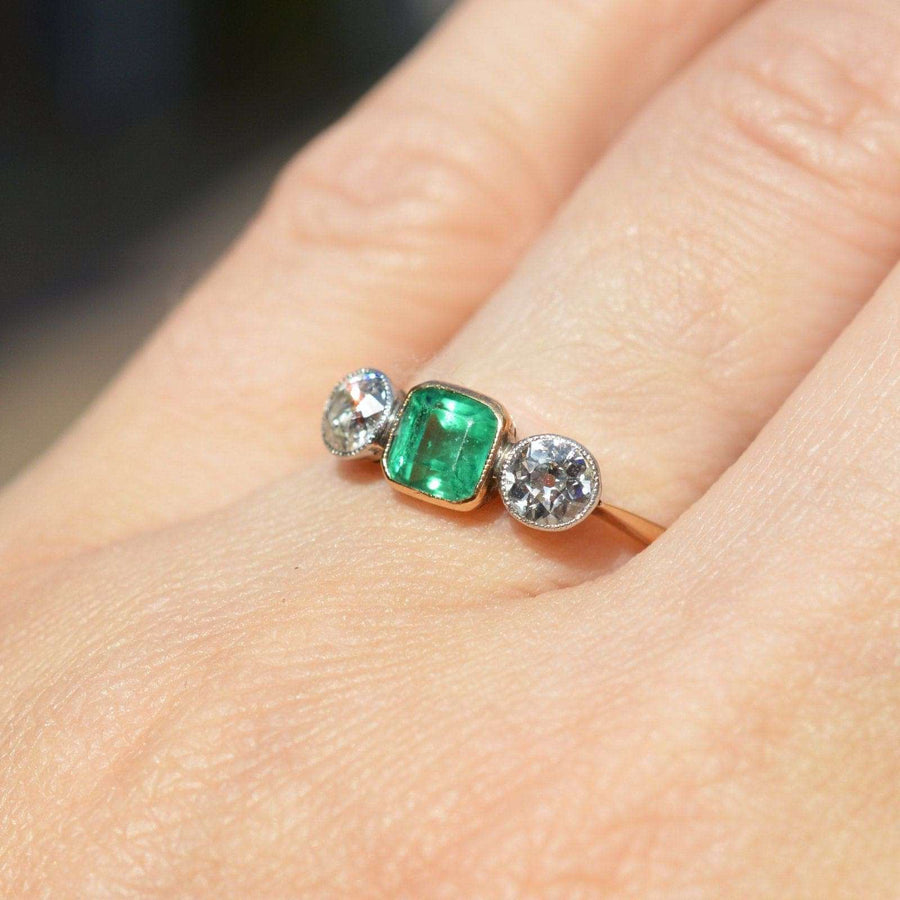 Edwardian gold and platinum three stone emerald diamond ring with vibrant green emerald and sparkling diamonds.