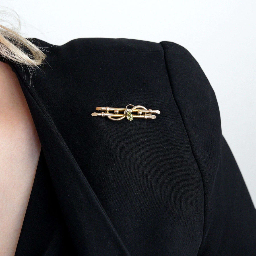 Edwardian 9ct gold bar brooch with pear shape peridot and seed pearls on a black jacket.