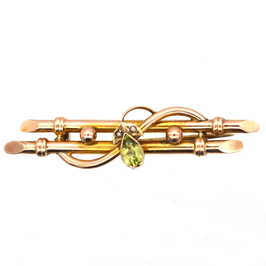 Edwardian 9ct gold bar brooch with pear-shaped peridot and seed pearls, featuring an elegant flower motif.