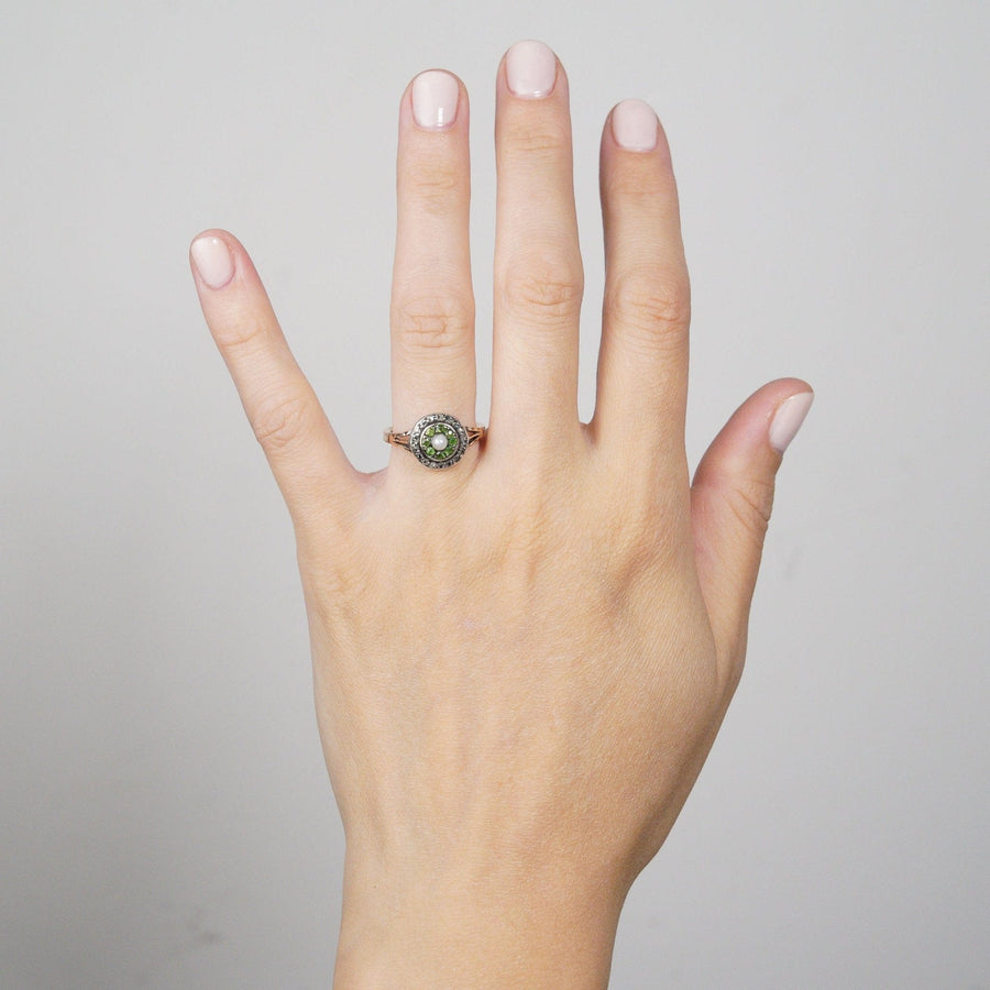 Edwardian 9ct gold target ring featuring green garnets, diamond accents, and a central natural pearl on a hand.