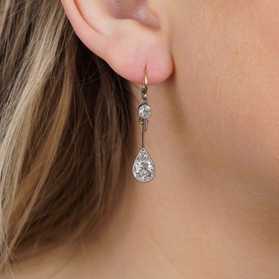 Edwardian platinum and gold diamond drop earrings, showcasing old cut diamonds in a pear-shaped design.