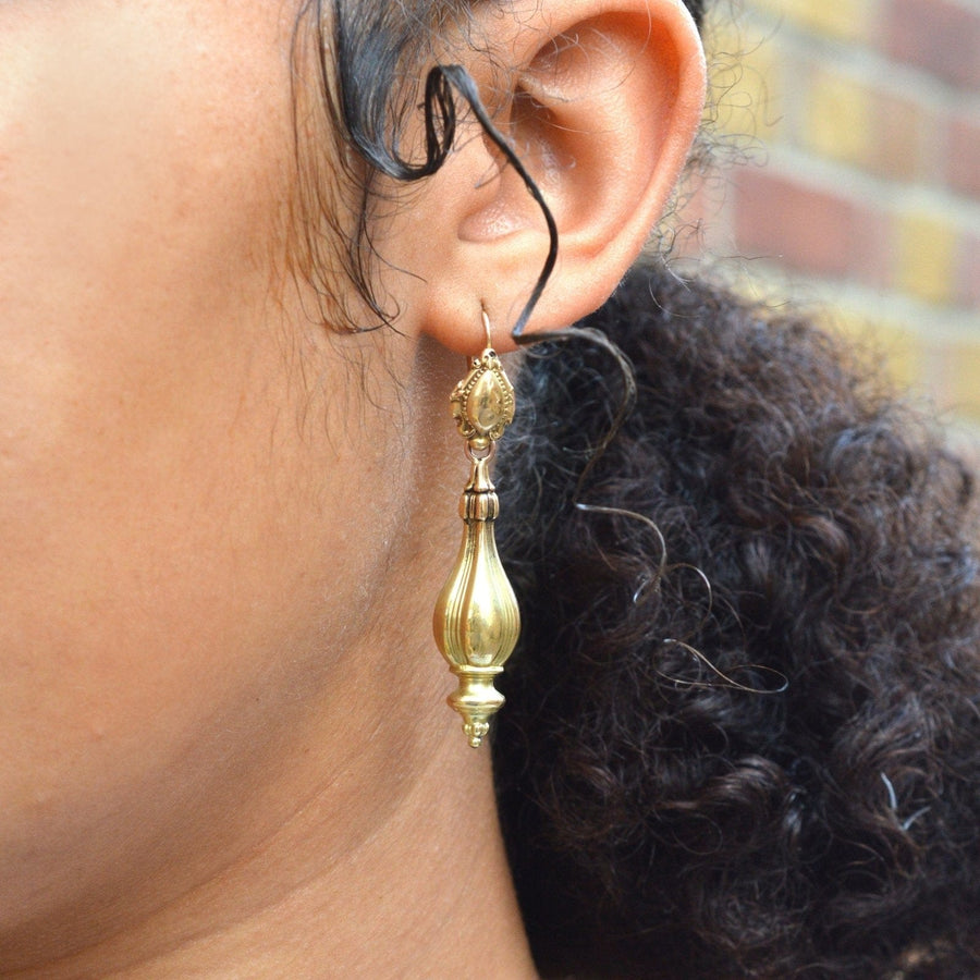 Close-up of 19th century 18ct gold 'Night and Day' drop earrings worn on a model's ear.