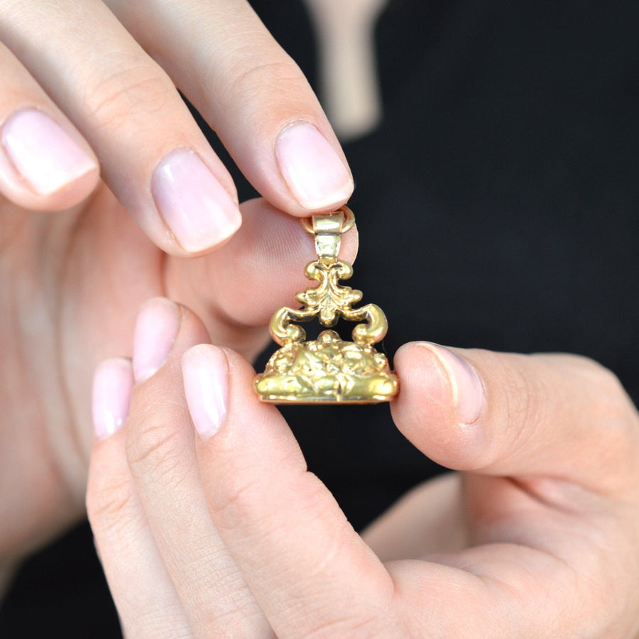 Georgian gold cased seal pendant with citrine intaglio monogram 'SC' held in hands.