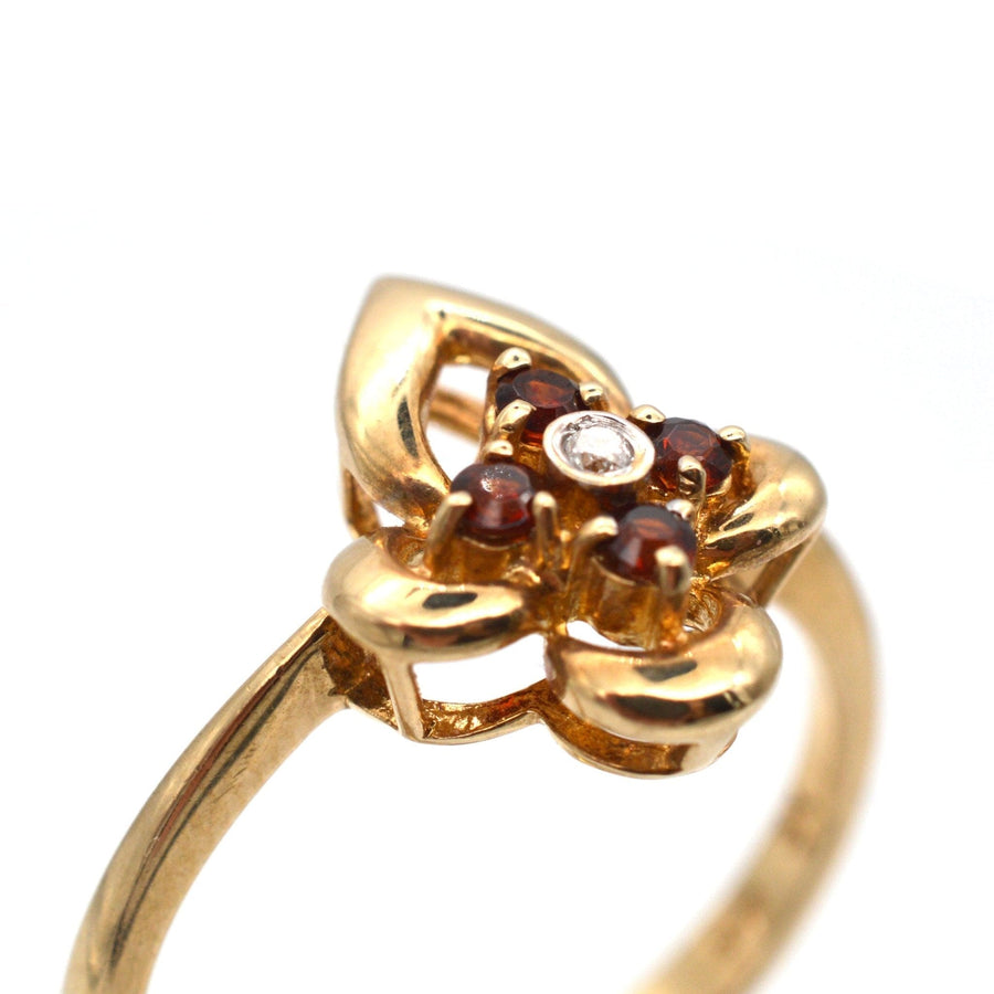 Late 20th century 18ct gold ring featuring hessonite garnets and a central diamond, shaped like a flower.