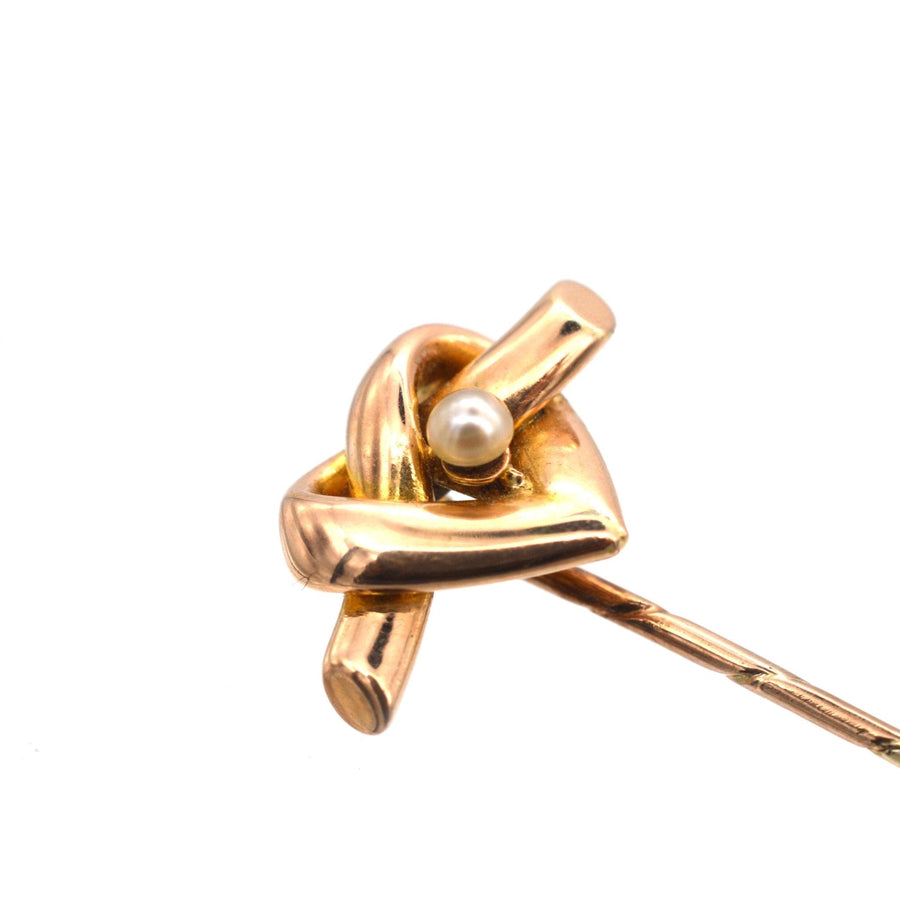 Late Victorian 15ct gold tie pin featuring a heart-shaped lover's knot and a natural pearl, dated 1880-1900.
