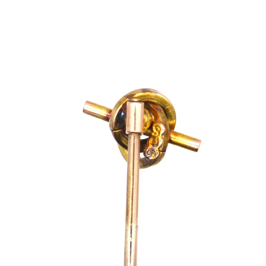 Late Victorian 9ct gold knot tie pin featuring a swirling design and garnet, symbolizing unity and eternity.