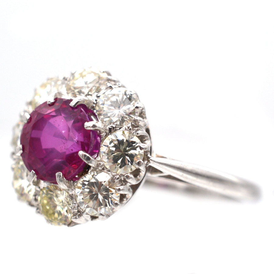 Mid 20th century platinum ring featuring a 1.7 carat Burma ruby surrounded by eight diamond clusters.