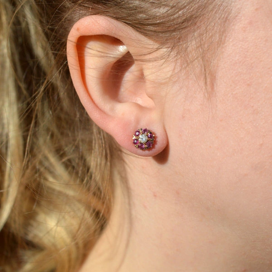 Mid century 14ct gold ruby and diamond cluster earrings worn on an ear, showcasing their elegance and detachable flower petal jacket.