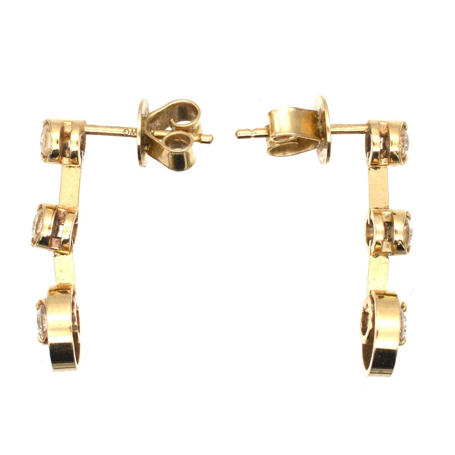 Modern 18ct gold three stone diamond drop earrings with bright white sparkly diamonds.