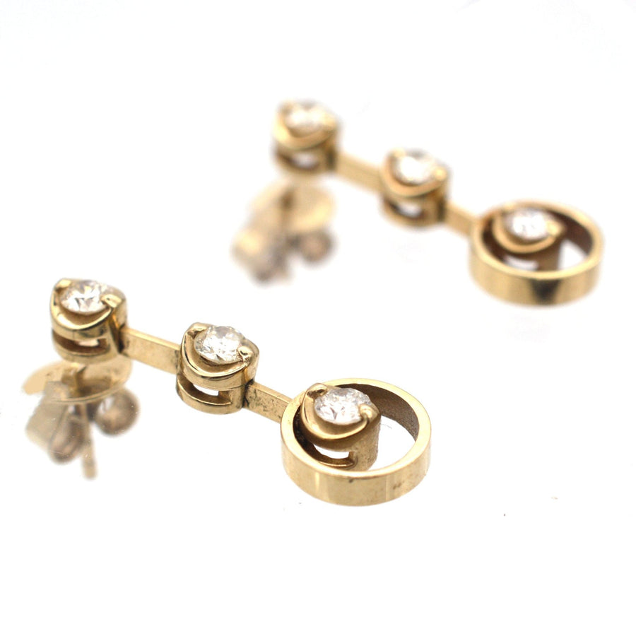 Modern 18ct gold three stone diamond drop earrings with bright white diamonds, ideal for weddings or formal occasions.