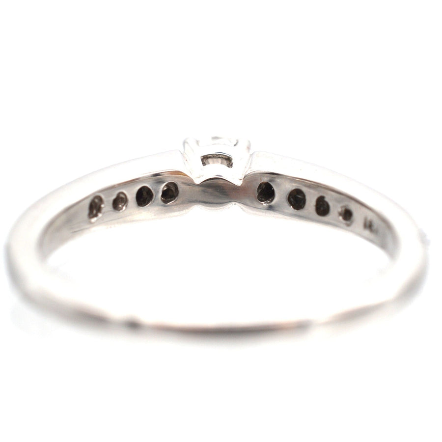 18ct white gold solitaire ring showcasing diamond shoulders and channel setting for a sleek, modern design.