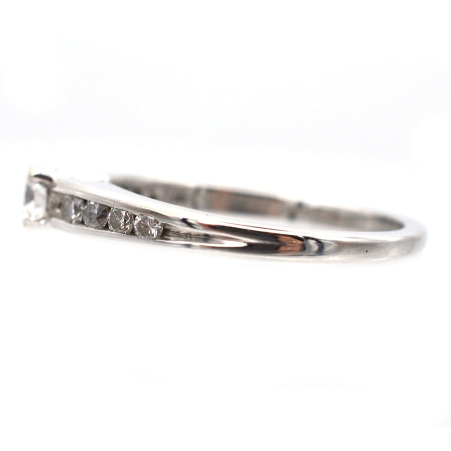Modern 18ct white gold solitaire ring featuring a brilliant cut diamond and channel-set diamond shoulders.