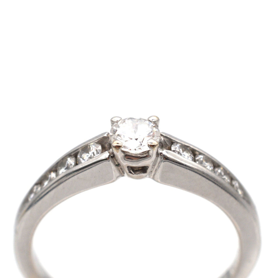 Modern 18ct white gold solitaire ring with diamond shoulders and a brilliant cut diamond center.