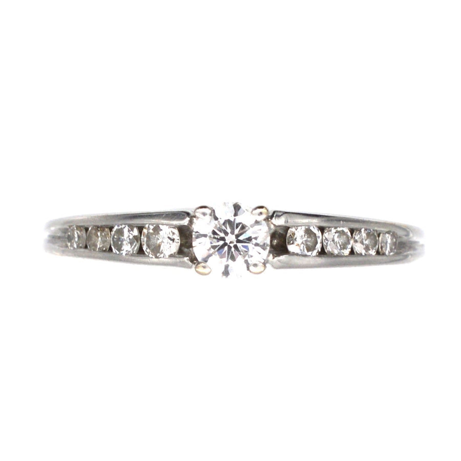Modern 18ct white gold solitaire ring featuring a brilliant cut diamond and diamond shoulders in channel setting.