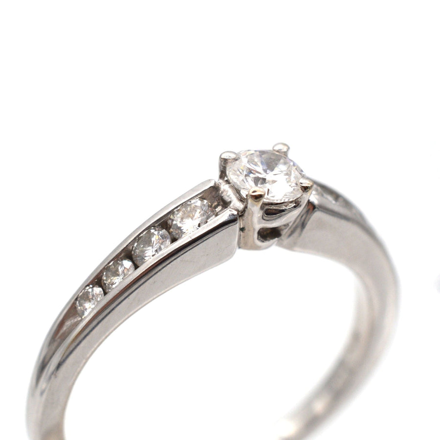 Modern 18ct white gold solitaire ring with diamond shoulders and brilliant cut diamond centerpiece.