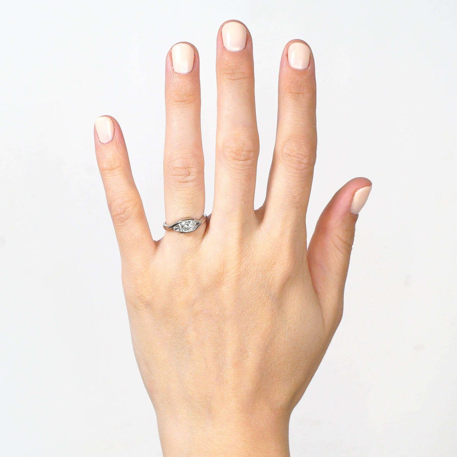 Hand displaying a modern 18ct white gold three stone diamond ring with cushion cut diamond.