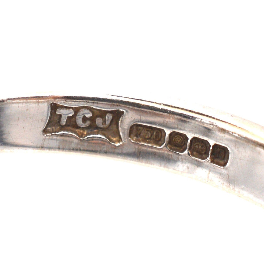 Close-up of hallmark and metal purity stamp on an 18ct white gold ring.