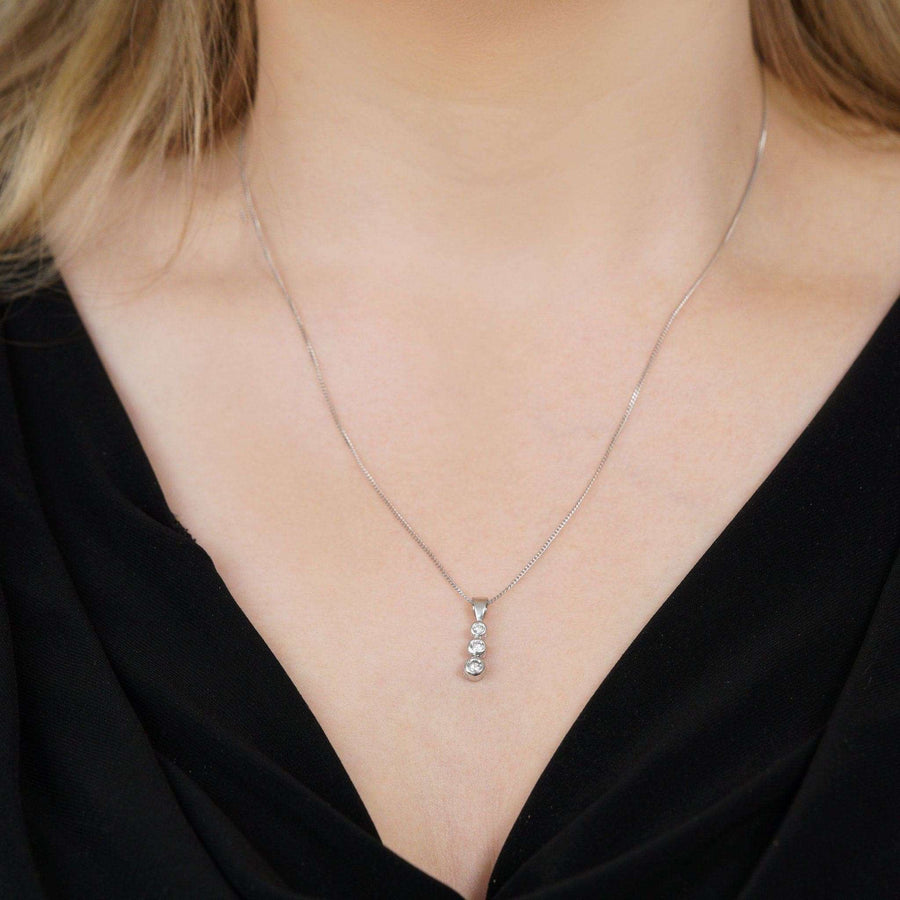 Modern platinum drop pendant necklace with three sparkling diamonds on a delicate platinum chain.