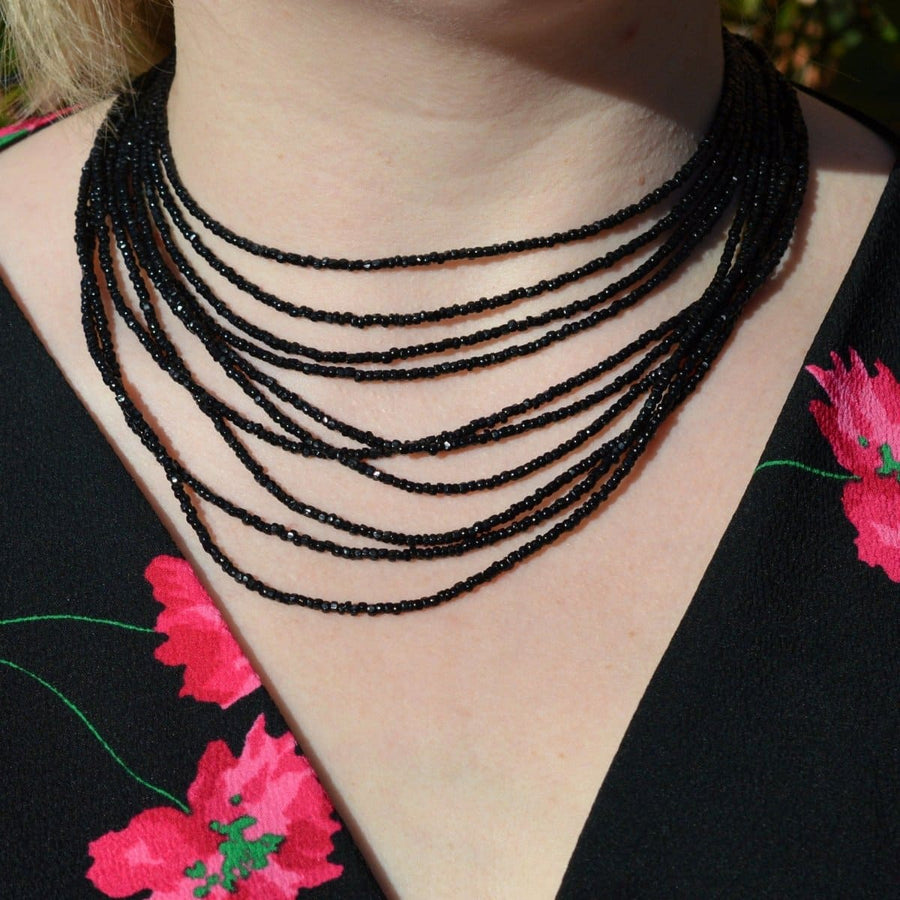 Vauxhall Glass multi-strand necklace featuring elegant black beads, worn elegantly against a floral dress.