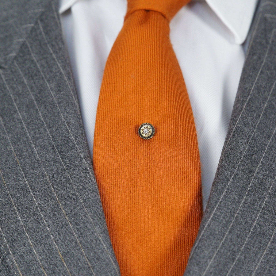 Victorian 15ct gold and diamond tie pin with star motif on an orange tie, showcasing timeless elegance.