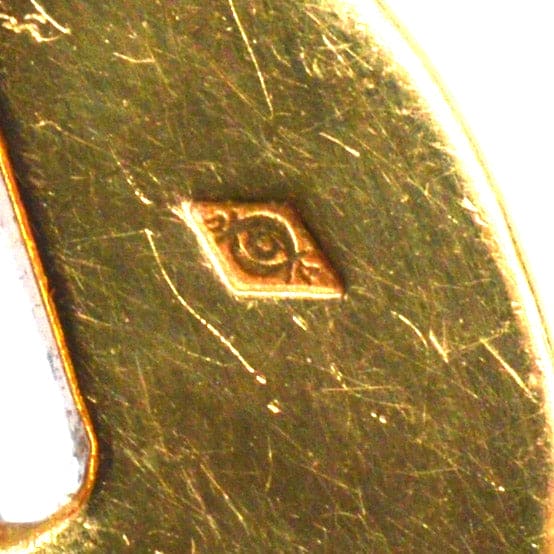 Nahaufnahme der Vintage-Punze von Cartier auf einem Goldschmuckstück, die die komplizierten Designdetails zeigt.