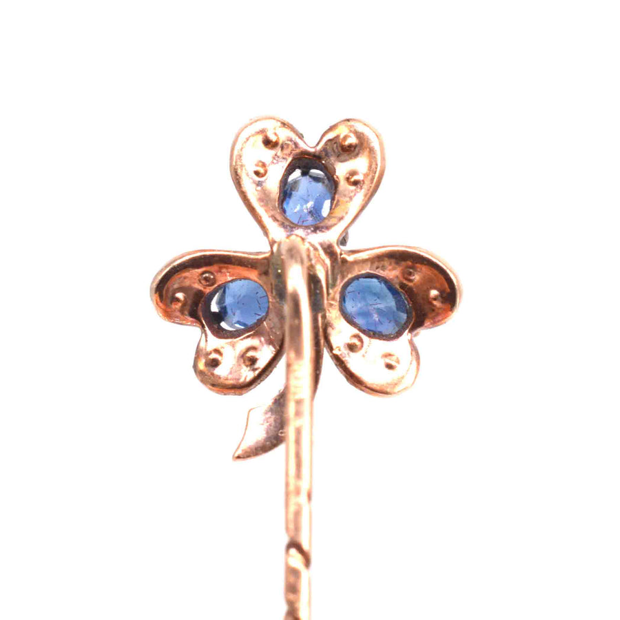 Close-up of early 20th century tie pin with three-leaf clover motif, blue sapphires set in 8ct gold.