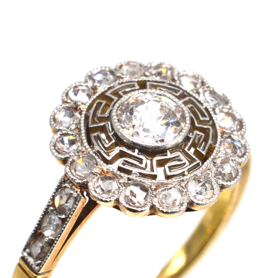 Ring aus 18 Karat Gold und Platin im Art-Déco-Stil mit Ziel-Diamanten und griechischen Schlüssel-Details, die die Eleganz des Jahrgangs unterstreichen.