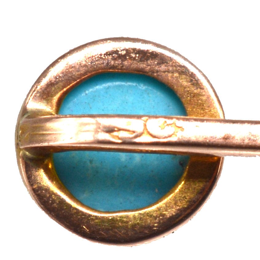 Nahaufnahme einer edwardianischen Krawattennadel aus 9-karätigem Gold, die einen leuchtenden Türkisstein in einer Millegrain-Fassung zeigt.