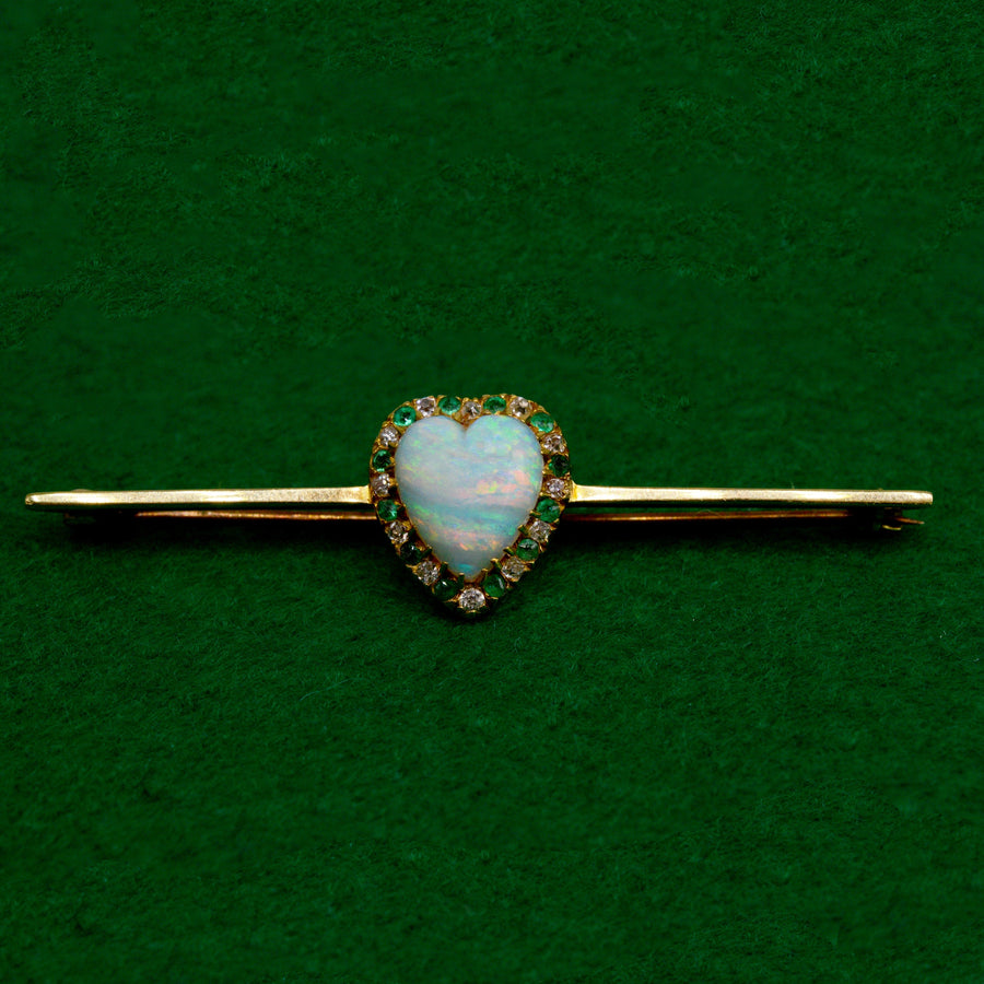 Viktorianische Barrenbrosche aus 18 Karat Gold mit herzförmigem Opal, Diamanten und Smaragden, Vintage-Schmuck auf grünem Hintergrund.