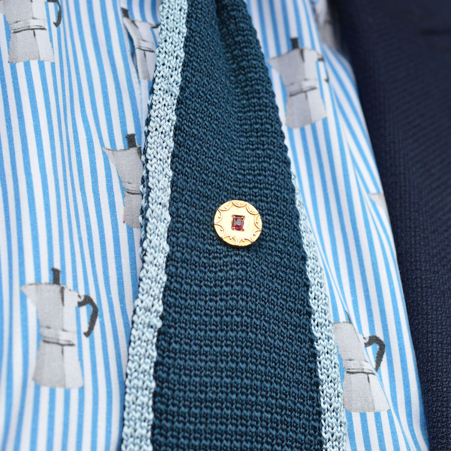 Victorian 15ct gold circle tie pin with ruby, worn on a silk tie, featuring elegant gold swirls, perfect accessory.