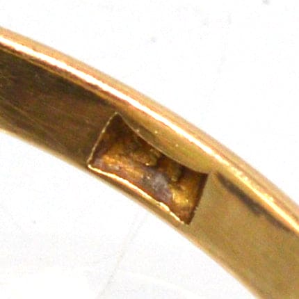 Nahaufnahme des Innenrings eines 18-karätigen Goldrings im Art-Déco-Stil, wobei die handwerkliche Verarbeitung und die Opalfassung hervorgehoben werden.