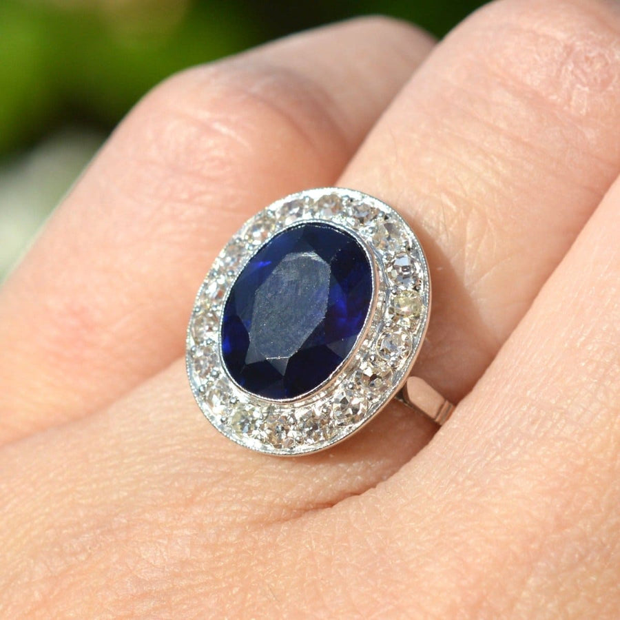 Platinring im Art-Déco-Stil mit synthetischem Saphir und Diamantcluster, der ein elegantes Design an einer Hand präsentiert.