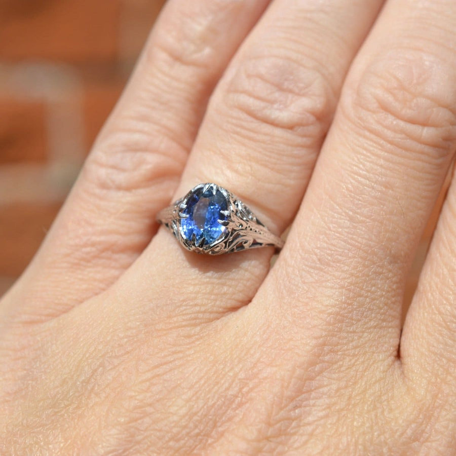 Belle-Époque-Ring aus 18 Karat Weißgold mit einem kornblumenblauen Saphir an einer Hand.