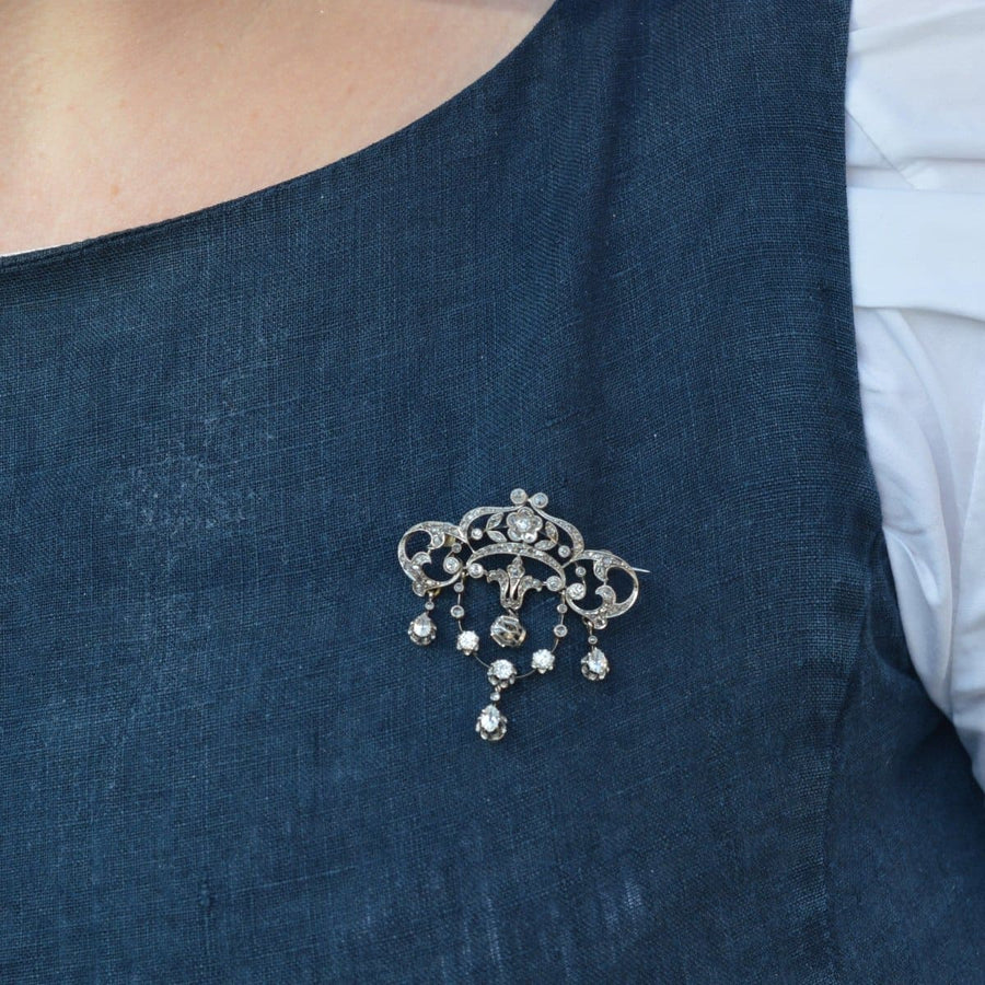 Belle-Epoque-Brosche aus 18 Karat Weißgold mit Diamanten, die an einem dunkelblauen Kleidungsstück getragen wird und florale Motive und Eleganz zeigt.