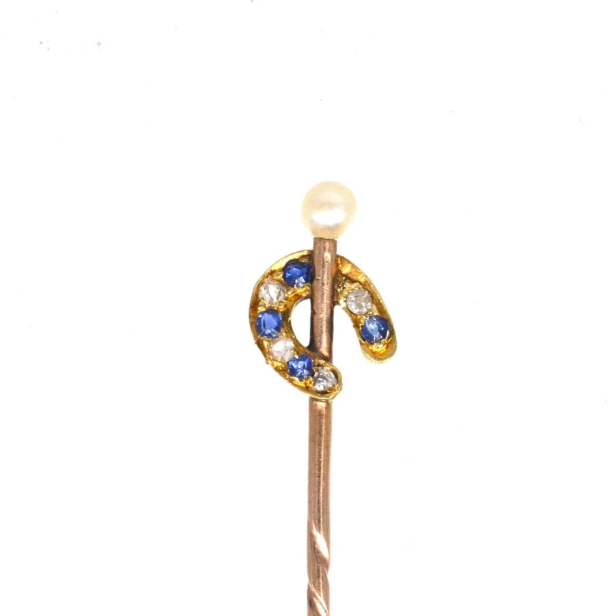 Edwardian gold horseshoe tie pin with sapphire, diamond, and pearl, symbolizing luck and protection.