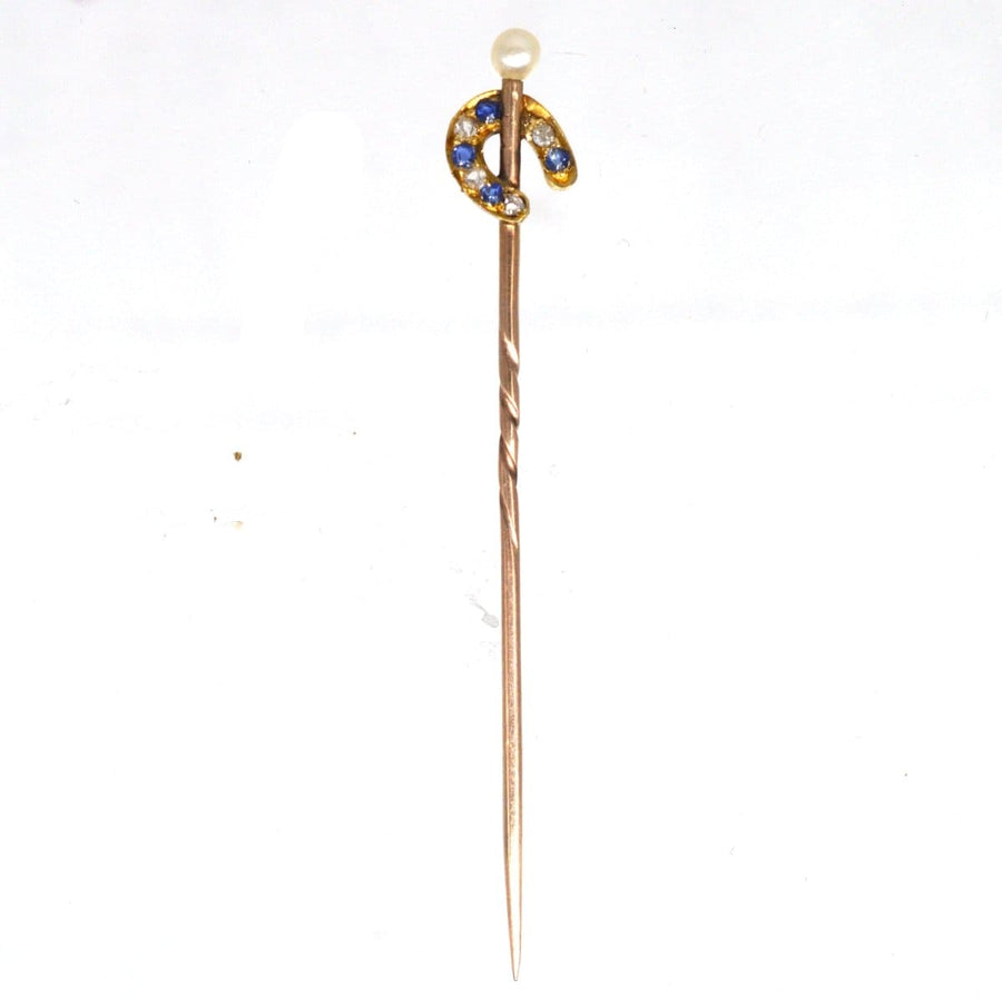 15ct gold horseshoe tie pin featuring sapphire, diamond, and a pearl, a symbol of luck from the Edwardian era.