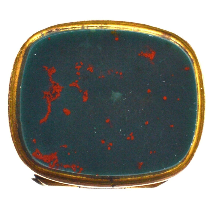 Top view of a vintage bloodstone seal pendant with red speckles in a gold setting.