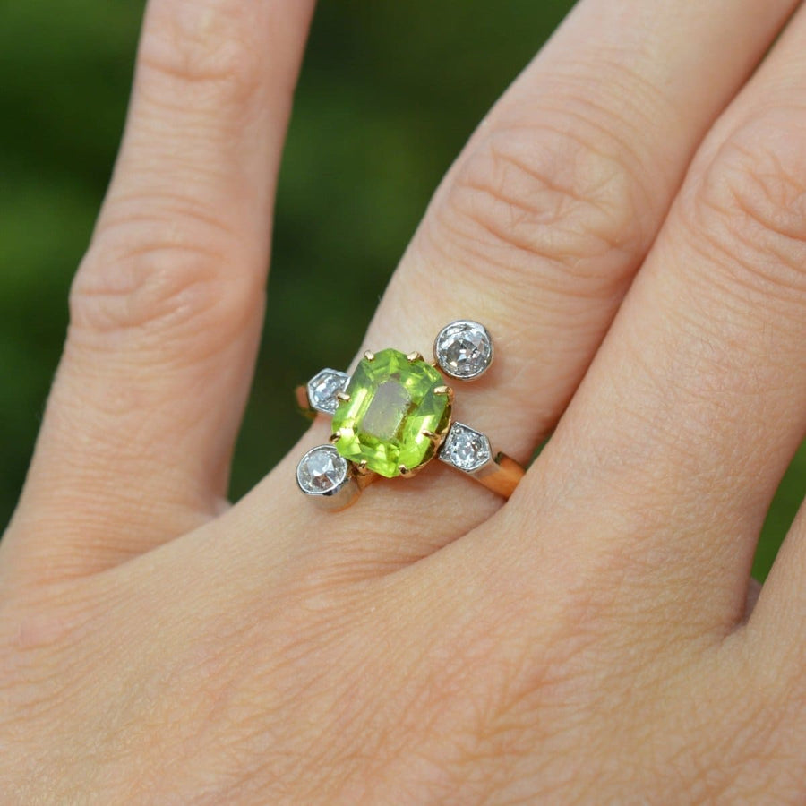Belle-Epoque-Ring mit Peridot und Diamanten an einer Hand, mit leuchtend grünem Peridot und funkelnden Diamanten.