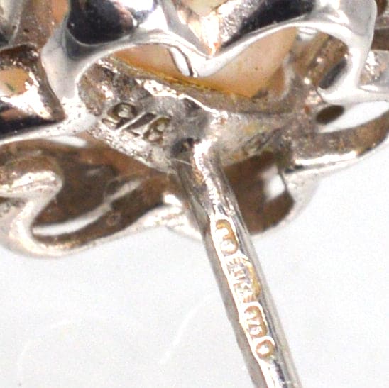 Nahaufnahme eines Sterncluster-Ohrrings aus 9 Karat Weißgold mit Perlen- und Diamantdetails.