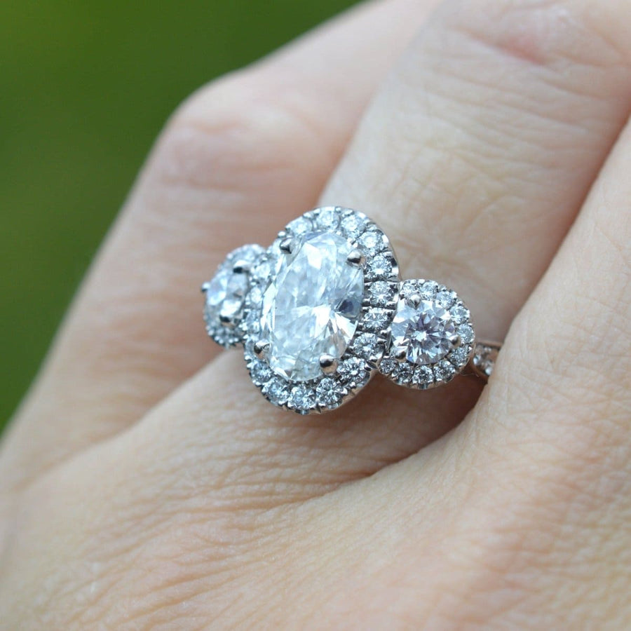 Moderner Dreistein-Diamantenring mit einem spektakulären ovalen Diamanten in der Mitte und zwei runden Steinen.