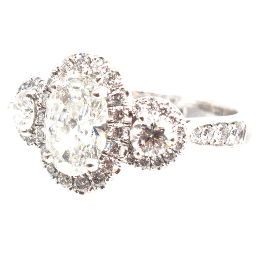 Moderner Dreistein-Diamant-Cluster-Ring mit einem Brillanten in der Mitte und Halo-Design, perfekt für Verlobungen.