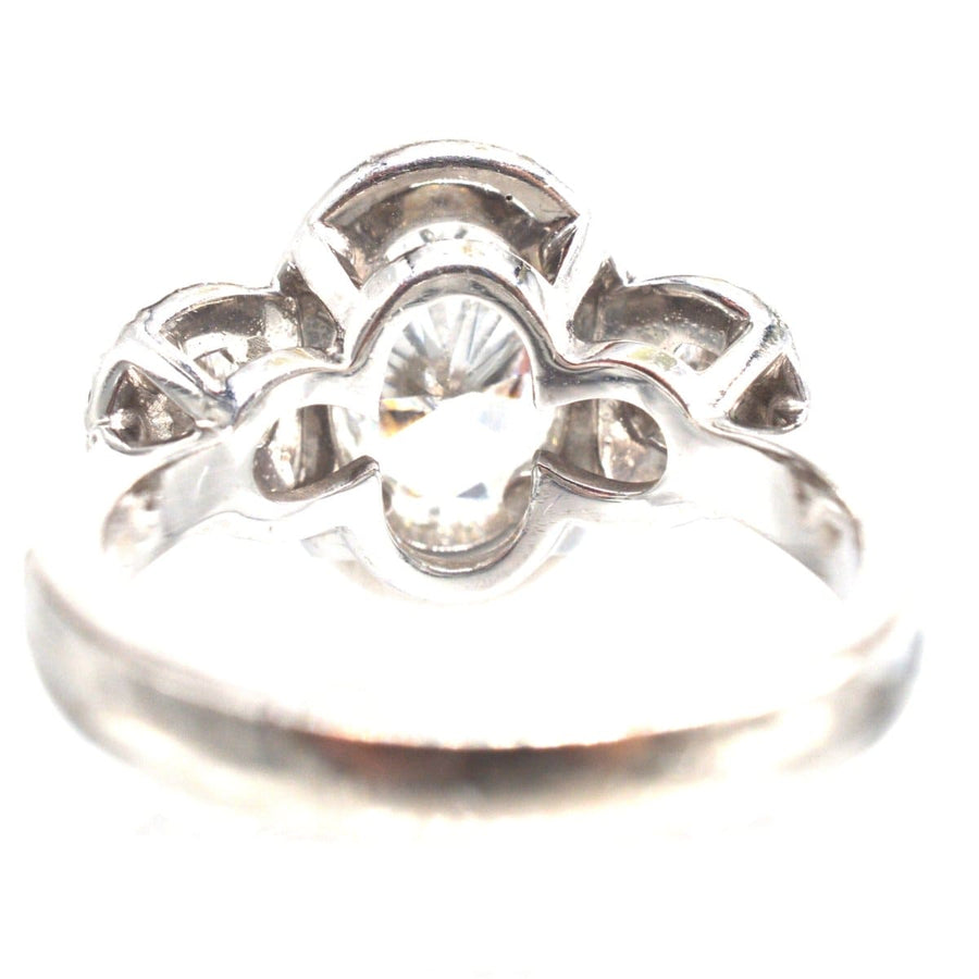 Moderner Dreistein-Diamant-Cluster-Ring mit einem Brillanten in der Mitte, der zeitlose Eleganz und Handwerkskunst ausstrahlt.