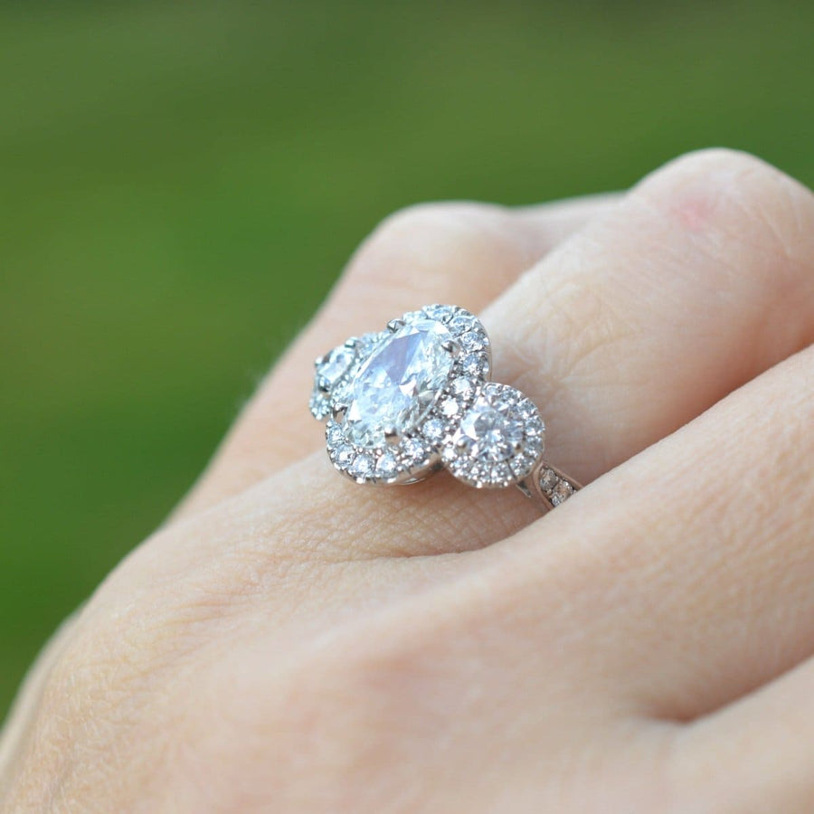 Moderner Dreistein-Diamant-Cluster-Ring mit einem atemberaubenden zentralen Diamanten und einem komplizierten Design an einer Hand.