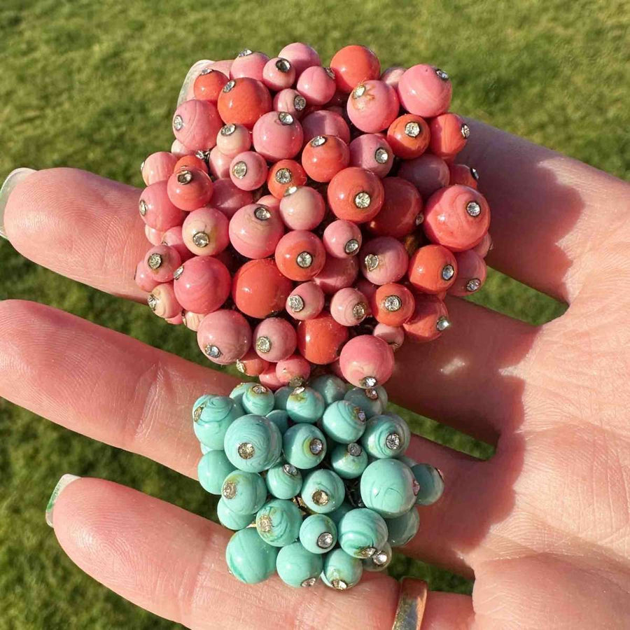 Seltene Gripoix-Brosche mit Glaspaste aus Koralle und blauem Türkis mit Strasssteinen auf einer Hand